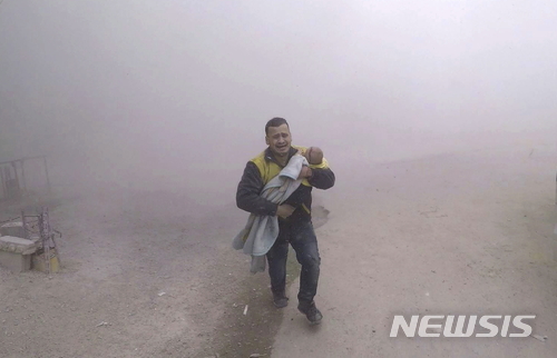 【다마스크수=AP/뉴시스】5일(현지시간) 시리아 다마스쿠스의 정부군 공습 현장에서 구조대원이 어린 아이를 구조하고 있다. 사진은 시리아민방위대(SCD) 제공. 2018.2.21. 