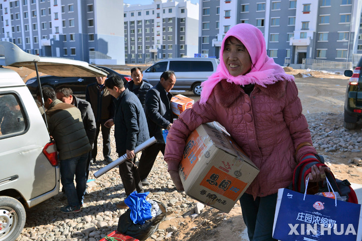 [구랑(중국)=신화/뉴시스]한 중국인 여성이 개인 소지품을 들고 중국 북서부 간쑤성의 구랑현에 있는 새 아파트로 걸어 들어가는 모습.2022.08.18.
