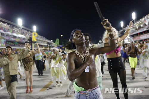 Members from the Beija Flor samba school parade perform a violence scene during Carnival celebrations at the Sambadrome in Rio de Janeiro Brazil, Tuesday, Feb. 13, 2018. Brazil's most famous city has long struggled with violence, particularly in the hundreds of slums controlled by drug traffickers, plus criminal assaults and increasing shootouts between drug traffickers and police. (AP Photo/Silvia Izquierdo)