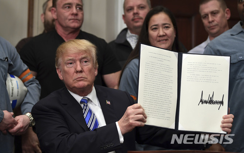 President Donald Trump holds up a proclamation on aluminum during an event in the Roosevelt Room of the White House in Washington, Thursday, March 8, 2018. He also signed one for steel. (AP Photo/Susan Walsh)