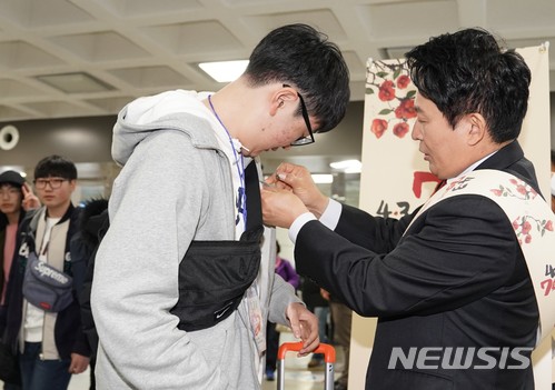 원희룡 제주지사가 지난 21일 제주공항에서 한 젊은이에게 동백꽃 배지를 달아주고 있다. <제주도 제공>