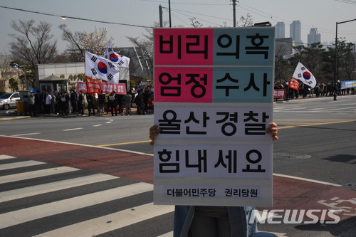 【울산=뉴시스】안정섭 기자 = 23일 오후 자유한국당 울산시당이 울산지방경찰청 앞에서 울산시장 측근이 연루된 아파트 공사비리 사건 수사 중단을 촉구하며 항의시위를 전개한 가운데 더불어민주당 관계자가 길 건너편에서 수사 지지 메시지를 담은 피켓을 들고 있다. 2018.03.23. yohan@newsis.com