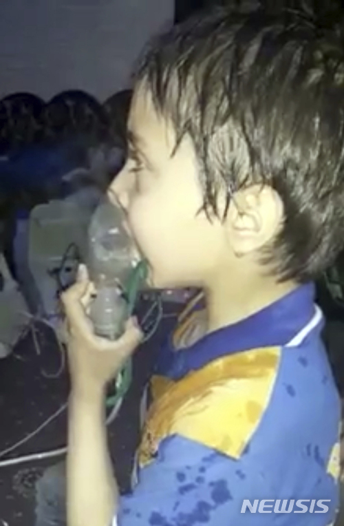 【구타(시리아)=AP/뉴시스】시리아 수도 다마스쿠스 외곽의 반군 점령 지역 동구타의 두마 지역에 독가스 공격이 가해진 가운데 8일 한 시리아 어린이가 산소마스크를 사용해 호흡하고 있다. 이 사진은 시리아 민방위대 '화이트 헬멧'이 제공했다. 2018.4.9