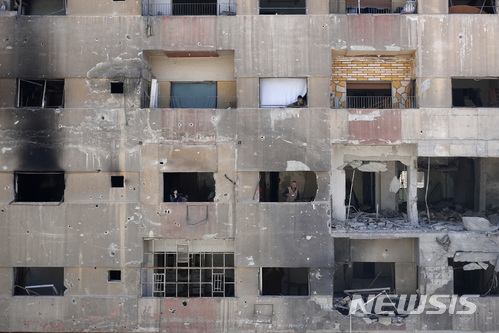 【두마=AP/뉴시스】16일(현지시간) 시리아 두마의 한 아파트에서 주민들이 바깥을 바라보고 있다. 이 아파트는 화학무기 의심 공격이 발생한 장소 근처에 있다. 아파트는 내전으로 인한 정부군과 반군의 충돌로 심하게 훼손된 모습이다. 2018.4.18.