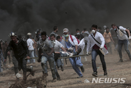 【가자시티=AP/뉴시스】팔레스타인 가자지구에서 20일(현지시간) 이스라엘군과 팔레스타인 시위대 간 충돌로 4명이 숨지고 150여 명이 다쳤다. 이날 팔레스타인 구호대원들이 한 부상자를 옮기기 있다. 2018.04.21 