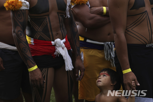 【브라질리아( 브라질)= AP/뉴시스】브라질의 원주민들이 수도 브라질리아에서 행하고 있는 연례 캠핑 시위 "자유의 땅 캠핑장"에서 한 어린이가 어른들의 모습을 올려다 보고 있다.  이 행사는 수 천명의 원주민들이 모여 연설과 토론, 항의 집회, 문화축제를 벌이는 것이지만 대개는 폭력시위와 강경진압으로 끝났다.       
