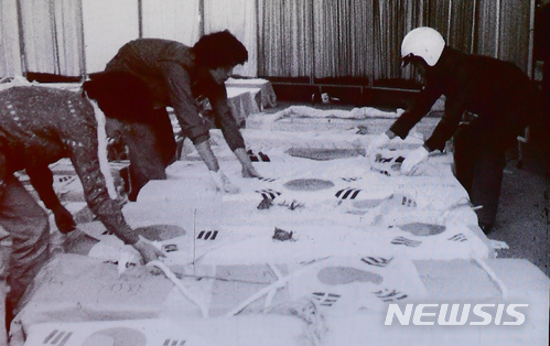 [광주=뉴시스] 1980년 5·18민주화운동 당시 시민들이 희생자들의 관을 태극기로 덮고 있다. 5·18민주화운동기록관 영상