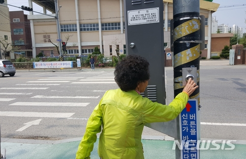 【영동=뉴시스】이성기 기자 = 충북 영동군이 영신중학교 앞 횡단보도 양측에 버튼식 보행자 작동 신호등을 설치했다. 지난 13일 한 주민이 신호등 버튼을 누르고 있다.2018.05.14(사진=영동군 제공) sklee@newsis.com