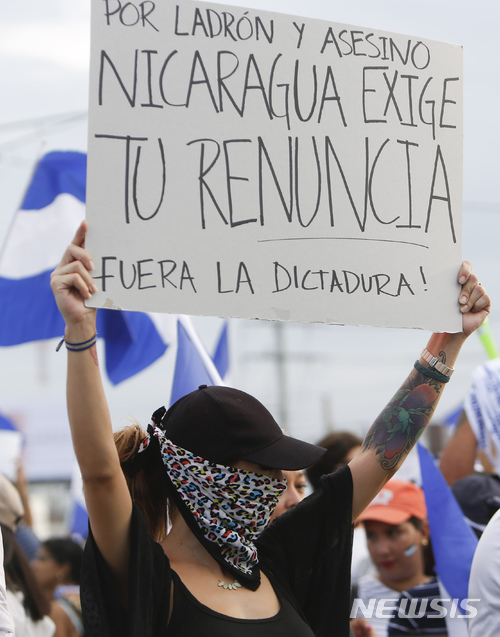 【마나구아=AP/뉴시스】니카라과 수도 마나구아에서 지난 해 5월 시위에 참가한 여성이 "살인자와 도둑, 니카라과는 당신의 하야를 요구한다. 독재와 함께 나가라"라고 쓴 종이를 들어보이며 반정부 시위를 벌이고 있다. 2018.05.16