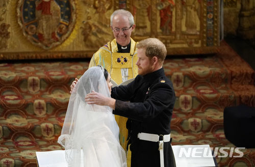 【런던=AP/뉴시스】19일(현지시간) 영국 윈저성에 있는 세인트 조지 교회에서 해리 왕자와 메건 마클의 '세기의 결혼식'이 열리는 가운데 해리 왕자가 신부 마클의 베일을 벗기고 바라보고 있다. 2018.05.19  