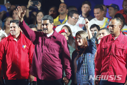 【카라카스(베네수엘라)=AP/뉴시스】니콜라스 마두로 베네수엘라 대통령과 부인 실리아 플로레스가 20일(현지시간) 선거위원회가 베네수엘라 대통령선거에서 마두로가 재선에 성공했다고 발표한 뒤 지지자들에게 손을 흔들며 인사하고 있다. 2018.5.21