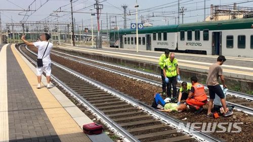 【서울=뉴시스】지난 5월26일 이탈리아 북부 피아센자의 한 기차역에서 한 젊은 남성이 기차에 치어 쓰러진 여성을 긴급 출동한 구조대가 응급처치하는 장면을 배경으로 셀카를 찍고 있다. 이 사진이 이탈리아 언론에 보도되자 이탈리아 사람들이 윤리의식 실종에 개탄과 함께 분노하고 있다. <사진 출처 : 영국 BBC> 2018.6.5