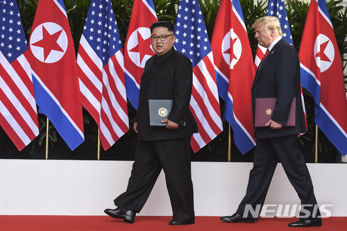 【싱가포르=AP/뉴시스】김정은 북한 국무위원장(왼쪽)과 도널드 트럼프 미 대통령이 12일 싱가포르 센토사섬의 카펠라 호텔에서 첫 북미 정상회담 후 합의문에 조인한 뒤 각자 서명한 합의문을 들고 퇴장하고 있다. 2018.6.12