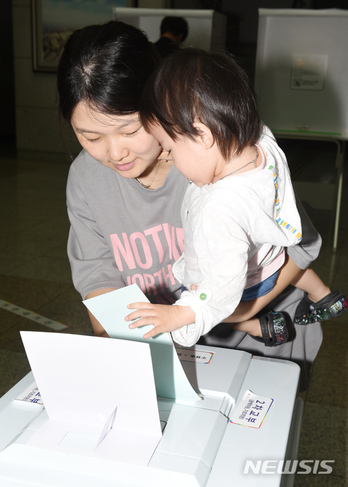 【울산=뉴시스】배병수 기자 = 제7회 전국동시지방선거일인 13일 오전 울산시 남구 삼산동 제5투표소에서 한 여성이 자녀와 함께 투표용지를 투표함에 넣고 있다. 2018.06.13. bbs@newsis.com.