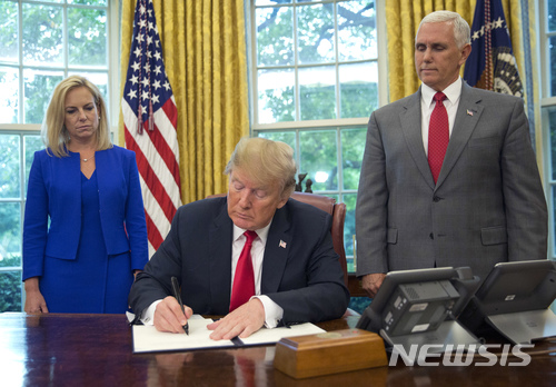 【워싱턴=AP/뉴시스】도널드 트럼프 미국 대통령(가운데)이 20일(현지시간) 불법이민 가족 분리 정책을 중단하기 위한 행정명령에 서명하고 있다. 2018.6.21.
