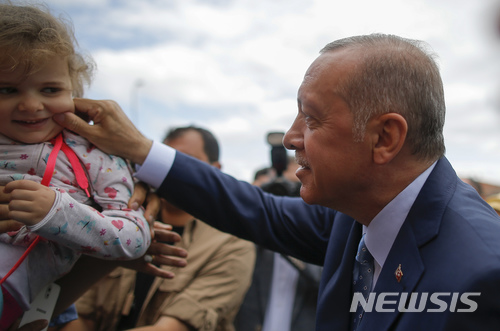 【이스탄불=AP/뉴시스】 터키의 레세프 에르도안 대통령이 24일 대통령선거 투표를 마친 뒤 투표하러 나온 부모가 안고있던 한 어린이의 볼을 꼬집으며 다정함을 표시하고 있다. 며칠 전 수백 만 명의 터키계가 살고있는 독일 주간지는 에르도안을 '독재자'라는 말과 함께 표지 인물로 조명했다. 2018. 8. 24.