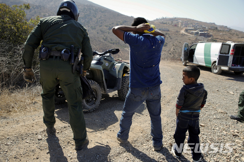 【샌디에이고 ( 미 캘리포니아주)= AP/뉴시스】 지난 해 멕시코 국경부근에서 과테말라에서 몰래 건너온 부자를 체포하는 미 국경수비대원.  
