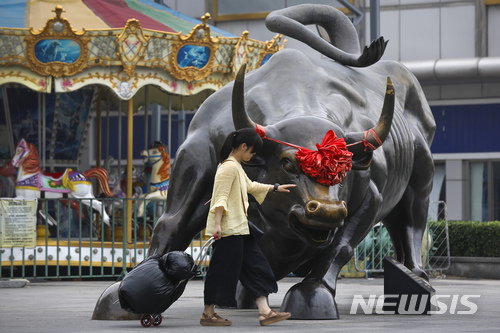 【베이징=AP/뉴시스】베이징의 한 쇼핑몰 앞에서 한 여성이 '황소장'을 상징하는 황소 동상을 만지고 있다. 2018.07.09