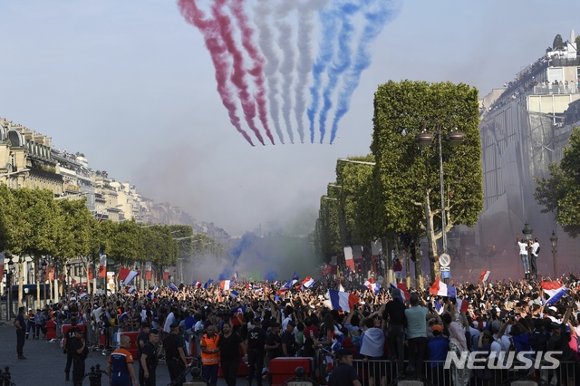 【파리 =AP/뉴시스】 러시아 월드컵 대회 우승컵을 안고 돌아온 프랑스의 월드컵 대표팀 차량행렬을 환영하는 파리 시민들 머리 위로 제트기 편대가 삼색기의 색깔을 연무로 뿜으며 날아가고 있다.   
