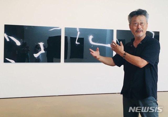 【서울=뉴시스】 박현주 미술전문기자 = 이창수 사진작가가 상형문자처럼 보이지만 찰나의 빛의 형상을 묘하게 잡아낸 사진 작품에 대해 이야기하고 있다.