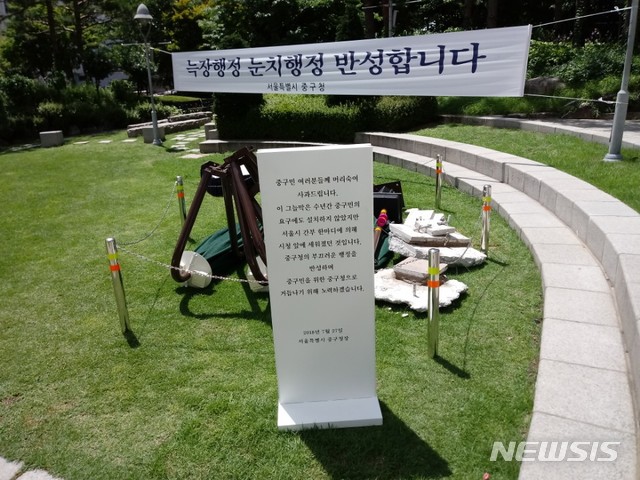 【서울=뉴시스】 손대선 기자 = 서울 중구가 30일 서울시청 광장 앞에 설치했다가 철거한 무더위 그늘막을 구청 잔디광장으로 옮겨 전시하고 있다. 중구는 그늘막 앞에 표지판을 세워 철거의 이유를 설명하고 있다.  sds1105@newsis.com  