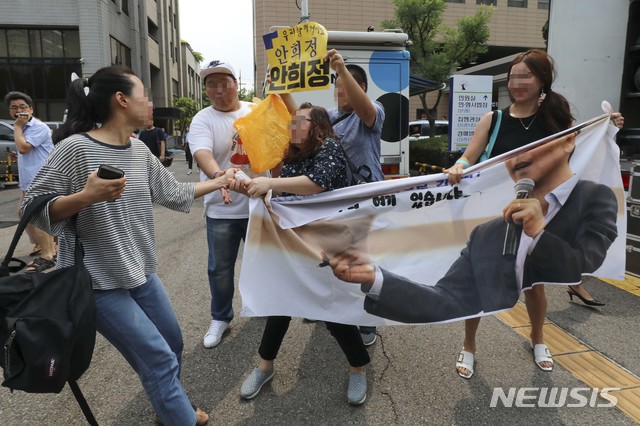 【서울=뉴시스】 조성봉 기자 = 성폭행 등의 혐의로 기소됐던 안희정 전 지사가 1심에서 무죄를 선고받은 14일 서울 마포구 서부지법앞에서 한 여성이 안희정 전 지사를 지지하는 사람들의 플래카드를 뺏으려하고있다. 2018.08.14.  photo@newsis.com