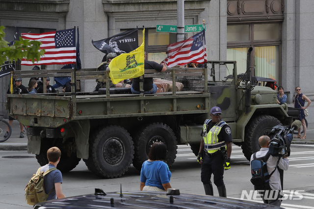 【 시애틀( 미 워싱턴주) = AP/뉴시스】총기규제에 반대하는 우익 단체들으, 시위대가 18일(현지시간)  대형트럭에 깃발을 타고 시애틀 시청 부근 거리에서 선전활동을 펴고 있다.   