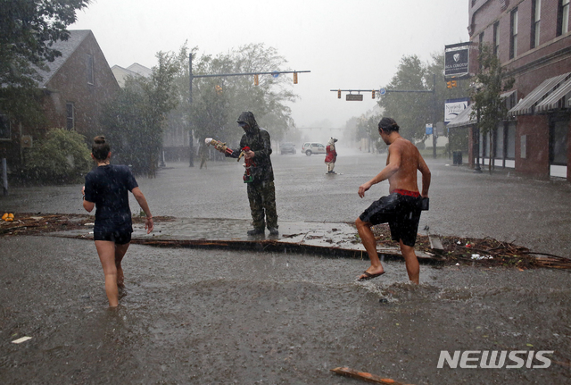 【뉴베른(노스 캐롤라이나주)=AP/뉴시스】미 노스 캐롤라이나주 뉴베른이 허리케인 플로렌스가 몰고온 폭우 및 폭풍 해일로 물에 잠긴 가운데 14일 주민들이 물 속에서 허리케인에 의한 피해 정도를 살펴보고 있다. 짐 트록던 교통장관은 윌밍턴과 샬럿 사이 지역은 1000년만에 한번 발생할 수 있는 대홍수에 직면할 것으로 우려된다고 말했다. 2018.9.15 