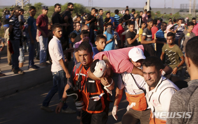 【가자지구= AP/뉴시스】가자지구 이스라엘 국경철책 부근에서 시위대의 구조반이 9월 18일( 현지시간) 이스라엘군의 발포로 총상을 입은 청년을 옮기고 있다.    