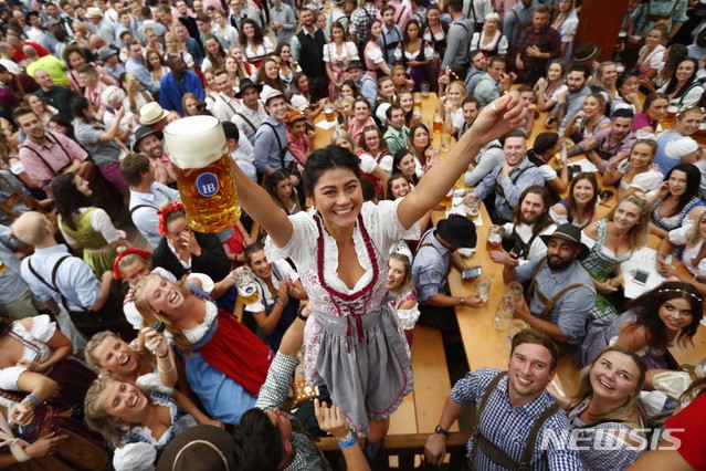【뮌헨(독일)=AP/뉴시스】독일 뮌헨에서 185회 옥토버페스트가 개막한 22일 한 젊은 여성이 맥주를 든 채 테이블 위에 올라서 전세계 최대 맥주 축제의 개막을 축하하고 있다. 2018.9.22