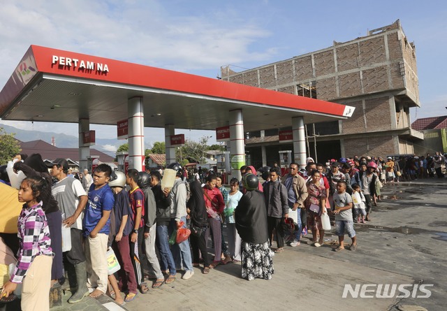 【팔루=AP/뉴시스】인도네시아 술라웨시 섬의 팔루에서 강진으로 인해 발생한 쓰나미가 휩쓸고 지나간 이후 30일 주민들이 가솔린을 받기 위해 줄지어 서있다. 2018.09.30 