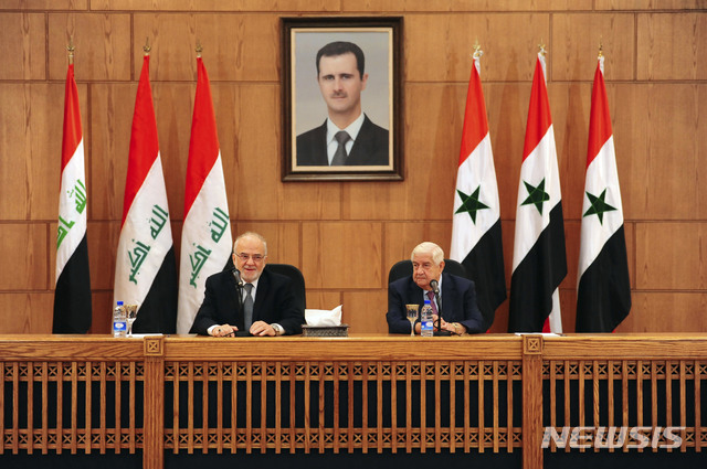 15일 시리아의 알모아렘 외무장관(오른쪽)이 이라크의 알자파리 외무장관을 맞아 공동 기자회견을 하고 있다. 시리아의 바샤르 아사드 대통령 사진이 내려다보고 있다  AP