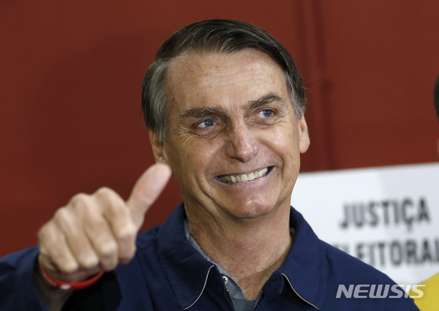 FILE - In this Oct. 7, 2018 file photo, presidential frontrunner Jair Bolsonaro, of the Social Liberal Party, flashes a thumbs up at a polling station in Rio de Janeiro, Brazil. In the first round of voting on Oct. 7, Bolsonaro performed far beyond expectations, nearly winning outright with 46 percent of the vote. (AP Photo/Silvia Izquierdo, File)