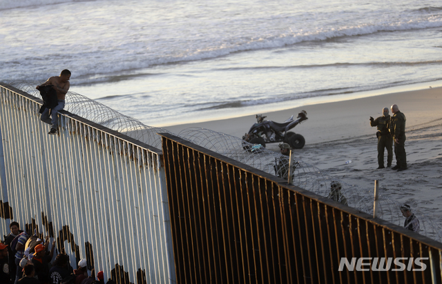 【티후아나=AP/뉴시스】미국 샌디에이고와 멕시코 티후아나 사이에 있는 국경 구조물 위에 14일(현지시간) 한 남성이 올라가 있다. 구조물을 사이에 두고 위쪽은 미국,아래쪽은 멕시코이다.  2018.11.15 