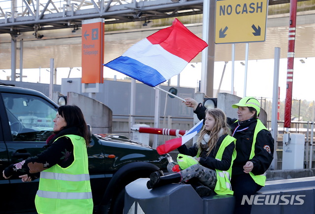 19일 프랑스에서 노란 재킷과 국기를 든 유류세인상 반대 시위자들이 고속도로를 점거한 뒤 시위에 이어 톨게이트를 열어주고 있다  AP 