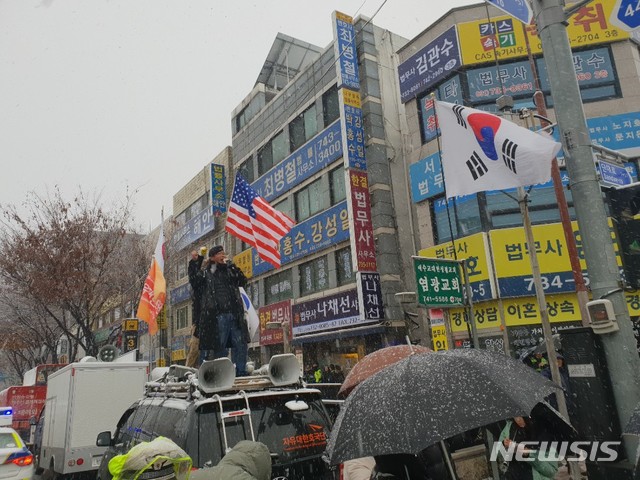 【수원=뉴시스】이병희 기자 = ‘태극기혁명국민운동본부’ 등 보수단체 회원들이 24일 오전 8시께 수원지방검찰청 성남지청 입구에서 5m 정도 떨어진 분당선 남한산성역 출구 앞에서 스피커를 켜고 “이재명을 구속하라” 등의 구호를 외치고 있다. 2018.11.24. heee9405@naver.com