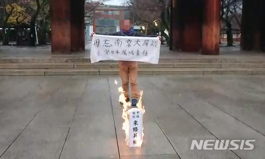 【서울=뉴시스】중국인 남성이 2018년 12월12일 오전 7시께 도쿄(東京) 지요다(千代田)구에 위치한 야스쿠니(靖國)신사 경내에서 A급 전범의 모형 묘비를 불태우고 있다. 그가 양손으로 들고 있는 팻말에는 중국어로 "난징대학살을 잊지말자"라고 쓰여있다.(사진출처: 홍콩 Caixin Global 홈페이지) 2018.12.12. 