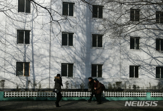 【평양=AP/뉴시스】19일 북한 주민들이 평양 시내의 한 아파트 앞을 지나고 있다. 2018.12.19