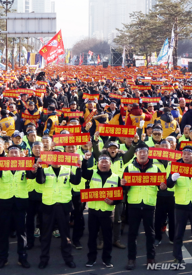 【서울=뉴시스】조성봉 기자 = 20일 오후 서울 영등포구 여의도 국회 인근에서 열린 '카카오 카풀 반대' 제3차 택시 생존권 사수 결의대회에서 참가자들이 ‘불법자가용 영업 카풀 퇴출' 손피켓을 들고 구호를 외치고 있다. 2018.12.20. suncho21@newsis.com