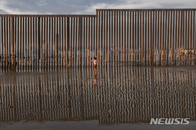 【티후아나=AP/뉴시스】 23일 멕시코 접경지 티후아나에서 한 소녀가 미국 샌디에이고 진입을 막고 있는 미국 국경 철기둥 펜스는 놔두고 앞의 태평양 바다를 향해 달려가고 있다. 아래는 태평양 해변 모래밭이다. 2018. 12. 23.