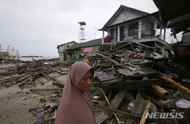 【수무르=AP/뉴시스】인도네시아 국가재난방지청(BNPB)이 28일 순다해협 쓰나미 사망자 수를 기존 430명에서 426명으로 정정했다. 사진은 지난 25일 쓰나미가 덮친 인도네시아 수무르 지역에서 한 주민이 파손된 가옥을 살펴보는 모습. 2018.12.28.
