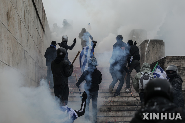 【아테네 = AP/뉴시스】 마케도니아의 국명에 반대하는 그리스 시민들이 20일 (현지시간)  그리스 아테네의 의사당 앞에서 진압경찰대에게 돌과 화염병을 던지며 격렬하게 싸우고 있다.   경찰은 이들에게 최루가스를 살포하며 강제 해산시켰다. 