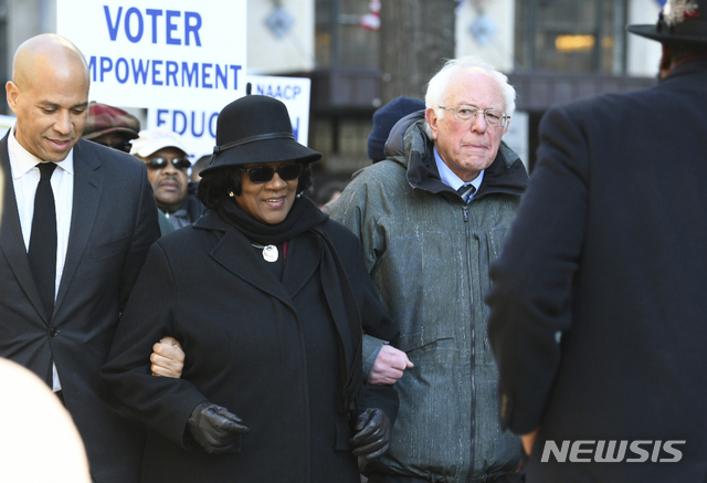 Following a Martin Luther King Jr. prayer service at Zion Baptist Church in Columbia, S.C., on Monday, Jan. 21, 2019, New Jersey Sen. Cory Booker, D-N.J., left, and Sen. Bernie Sanders, I-Vt., right walk with NAACP President Brenda Murphy during a march to the Statehouse. (AP Photo/Meg Kinnard)