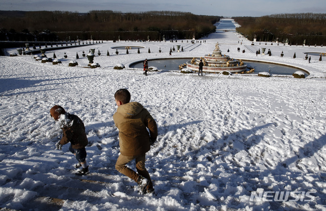 Tourists play in the snow-covered gardens of the Chateau de Versailles, west of Paris, Wednesday, Jan. 30, 2019. Snow blanketed the city on Wednesday as a winter storm brought several centimeters of snow across parts of Europe. (AP Photo/Christophe Ena)