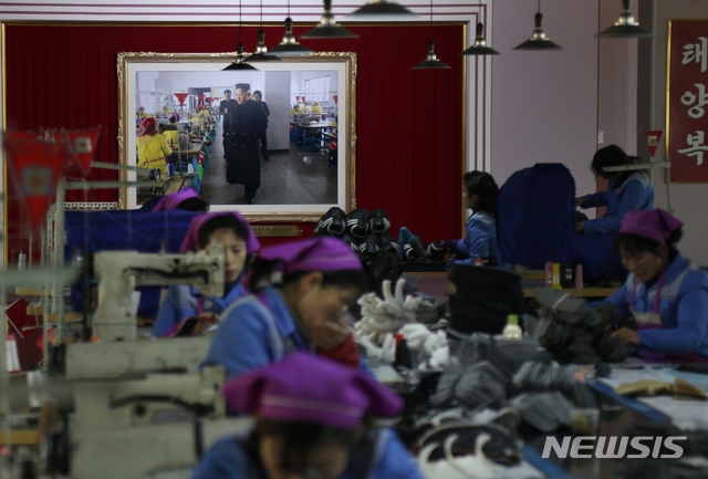【평양=AP/뉴시스】1일 평양의 류원 신발공장에 김정은 북한 국무위원장의 현지지도 사진이 걸려 있는 가운데 직원들이 신발 만드는 작업을 하고 있다. 2019.02.01.