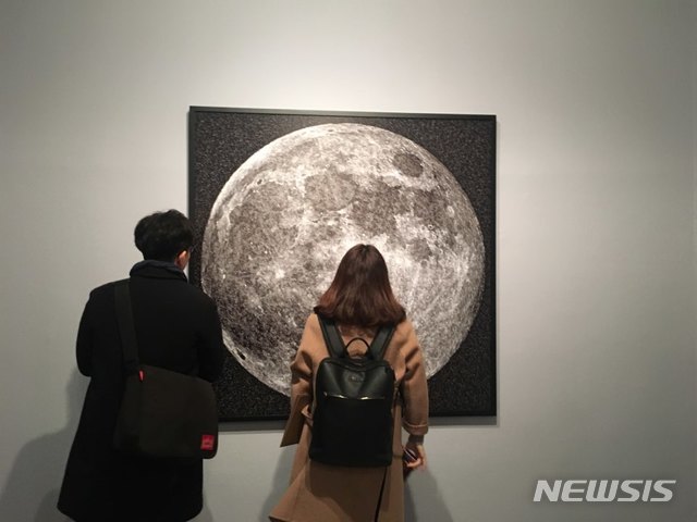 【서울=뉴시스】 박현주 미술전문기자 = 보름달이나 지구로 보이지만 다가서 보면 온갖 신용카드를 이어 붙인 작품이다.