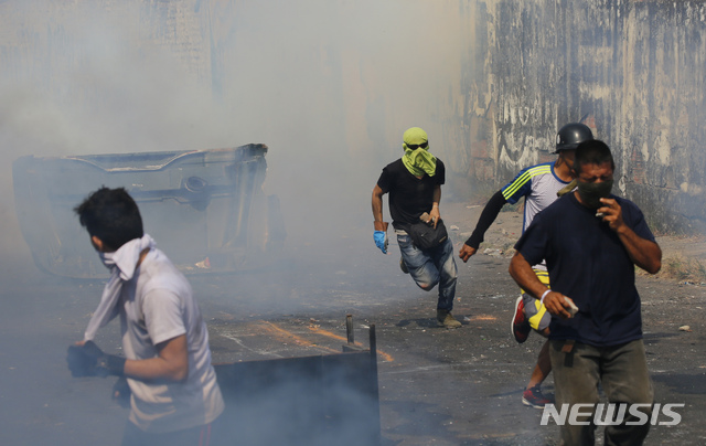 Demonstrators run away from a cloud of tear gas during clashes with the Bolivarian National Guard in Urena, Venezuela, near the border with Colombia, Saturday, Feb. 23, 2019. Venezuela&#039;s National Guard fired tear gas on residents clearing a barricaded border bridge between Venezuela and Colombia on Saturday, heightening tensions over blocked humanitarian aid that opposition leader Juan Guaido has vowed to bring into the country over objections from President Nicolas Maduro. (AP Photo/Fernando Llano)