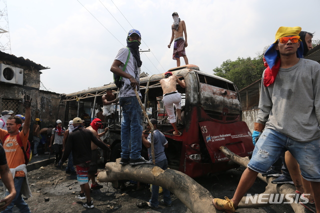 【우레나=AP/뉴시스】23일(현지시간)베네수엘라 우레나에서 시민과 군이 충돌한 가운데 성난 시민들이 불에 탄 버스에 올라타고 있다.  이날 새벽 콜롬비아 접경지역인 베네수엘라 우레나에서는 구호 물품을 반입하려는 야당 인사들과 자원봉사자, 시민들이 이를 저지하는 군과 충돌했다. 베네수엘라 국경수비대는 우레나의  국경 다리에서 구호물자 수송 트럭의 통행을 위해 바리케이드를 치우려는 시민들에게 최루탄을 쏘아댔다. 