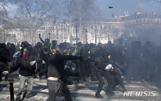 【파리=AP/뉴시스】18번째 주말 연속 노란조끼 반정부 시위가 열린 16일 프랑스 파리에서 시위대가 자욱한 연기 속에서 진압경찰과 충돌하고 있다. 한동안 수그러들던 노란조끼 시위가 이날 대규모 방화 등 다시 격화됐다. 경찰은 192명을 체포했으며 60명이 부상했다고 밝혔다. 2019.3.17