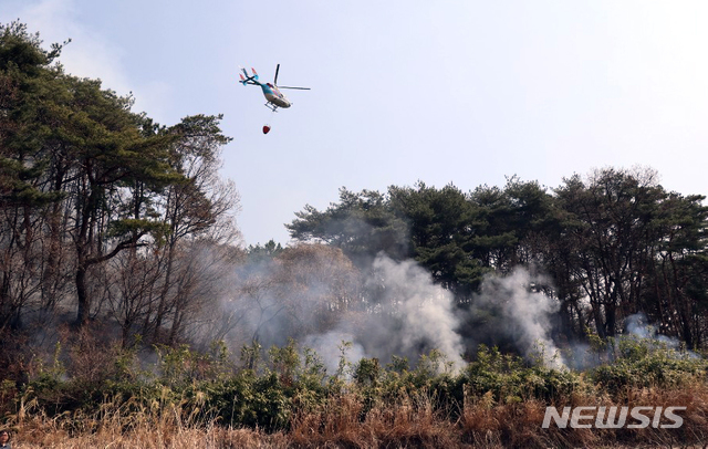 【부산=뉴시스】 3일 오전 부산 해운대구 운봉산 일대 산불 현장에서 이틀 동안 진화작업이 펼쳐지고 있는 가운데 헬기가 물을 뿌리고 있다.  부산소방재난본부는 이날 오전 9시 10분께 큰 불길을 잡고 잔불정리를 펼치고 있다고 밝혔다. 2019.04.03. (사진=부산소방본부 제공)  photo@newsis.com 